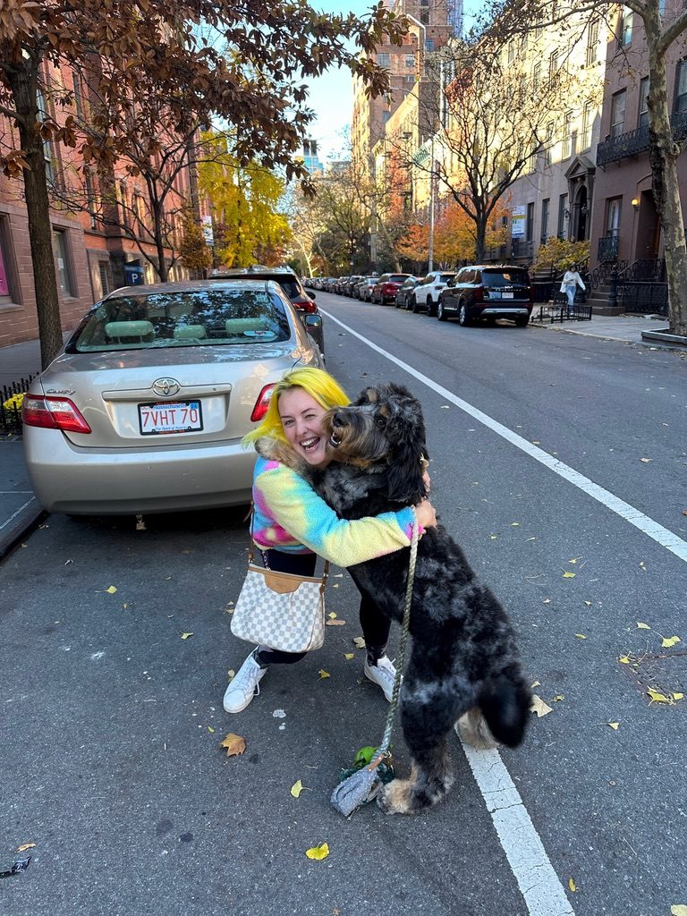 Britta hugging a dog on a Manhattan brownstone street